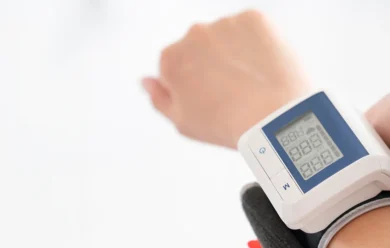 Osoba mająca na nadgarstku cyfrowy ciśnieniomierz z ekranem LCD wyświetlającym cyfry.