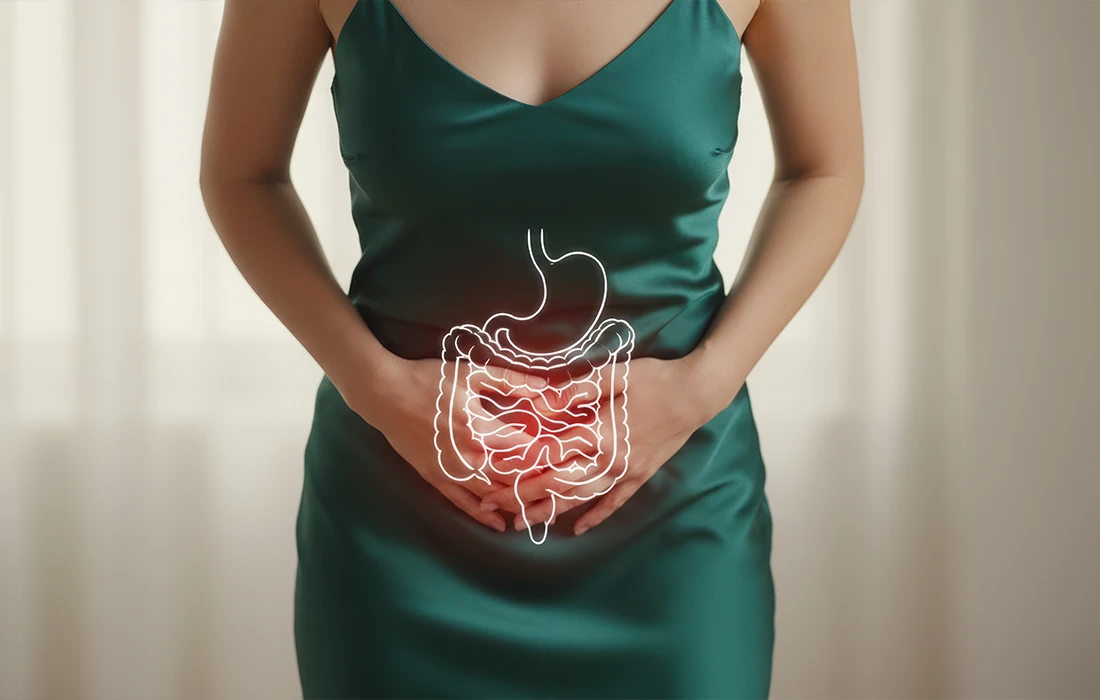 Kobieta w zielonej sukience trzyma się za podbrzusze, z ilustrowaną nakładką układu trawiennego podkreślającą jelita.