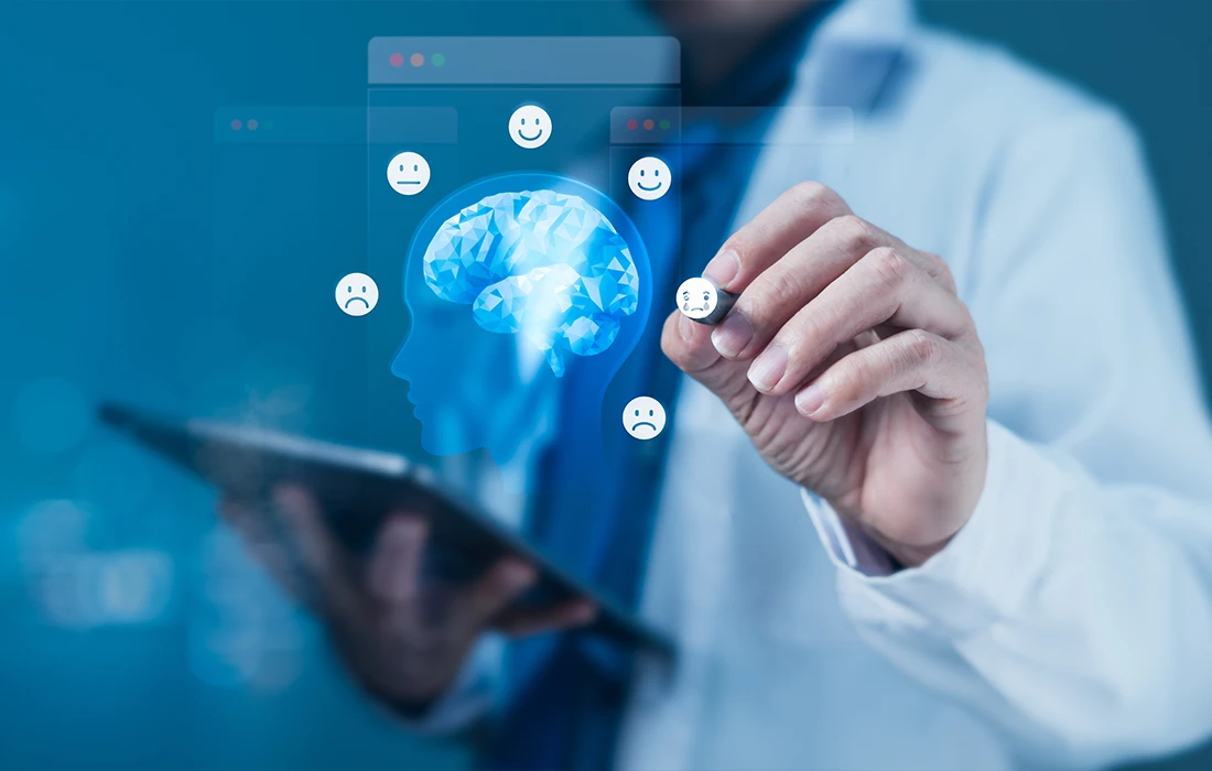 Osoba w fartuchu laboratoryjnym używa tabletu; cyfrowe ikony mózgu i różne wyrazy twarzy unoszą się w powietrzu, symbolizując ocenę zdrowia psychicznego.