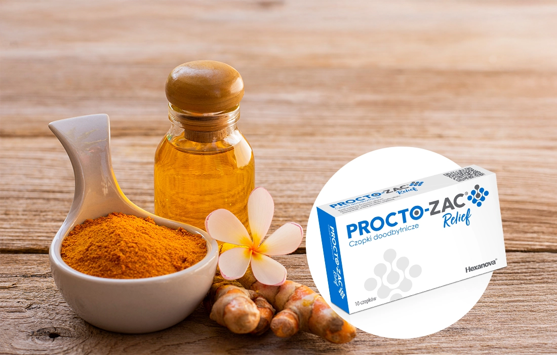 Miska kurkumy w proszku, korzenie kurkumy, mała butelka oleju, biały kwiat i pudełko czopków Procto-Zac Relief na drewnianej powierzchni.